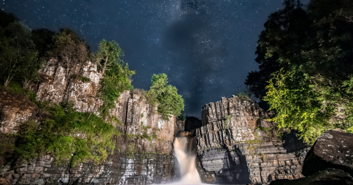 View of the Milky Way and starry night above High Force Waterfall in County Durham.